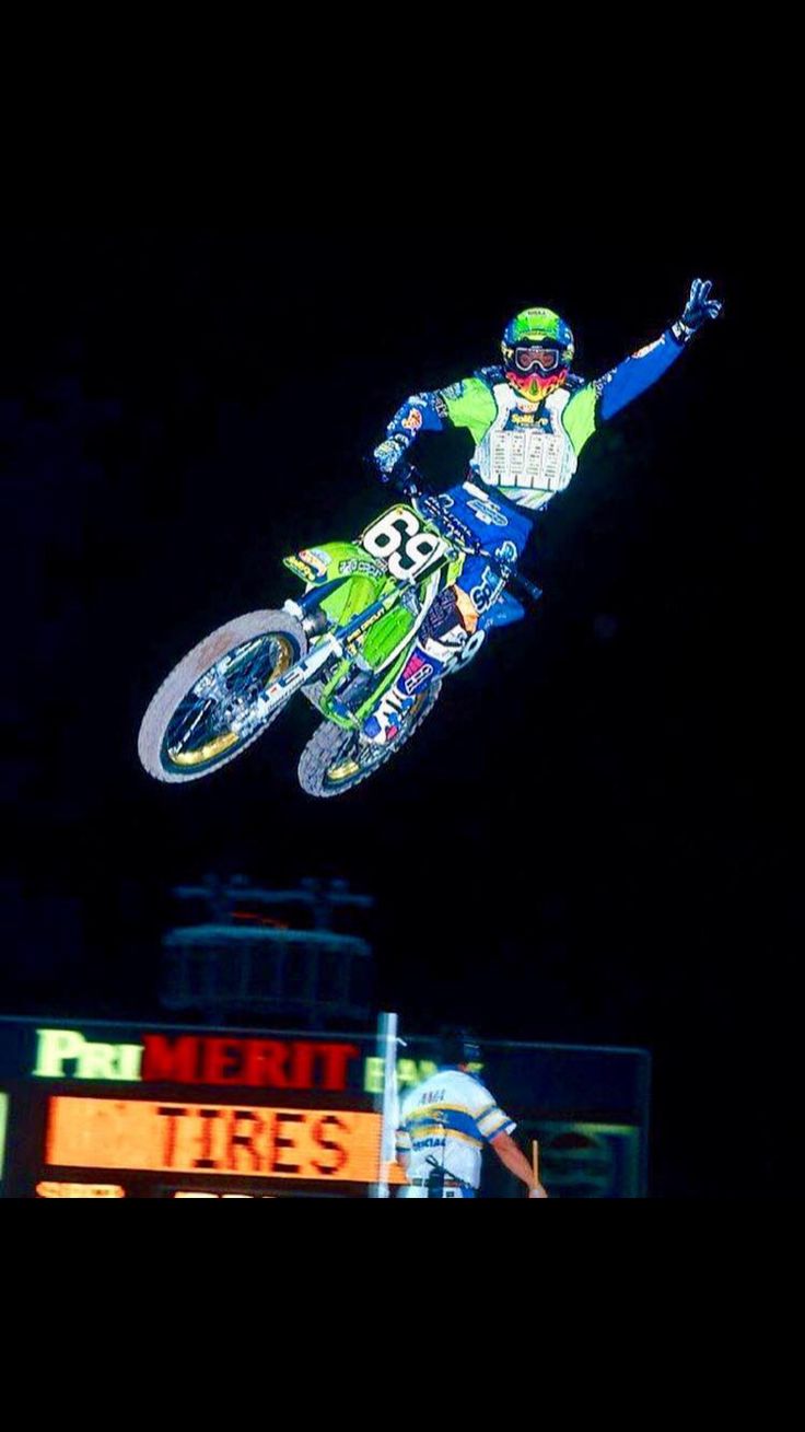 a person on a dirt bike in the air over a sign that says merri tires