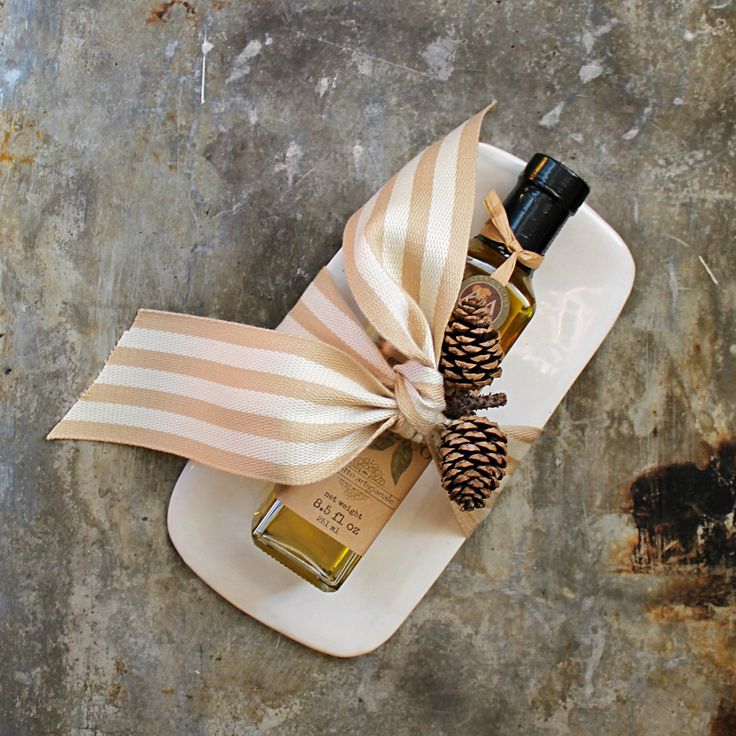 a bottle of olive oil tied to a plate with a pine cone and ribbon on it