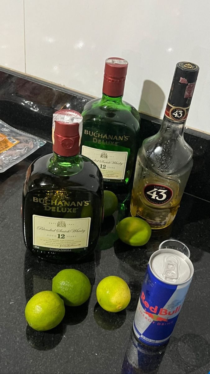 three bottles of alcohol sitting on top of a counter next to limes