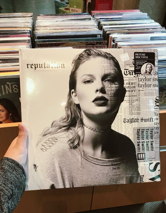 a person holding up a magazine in front of a stack of records