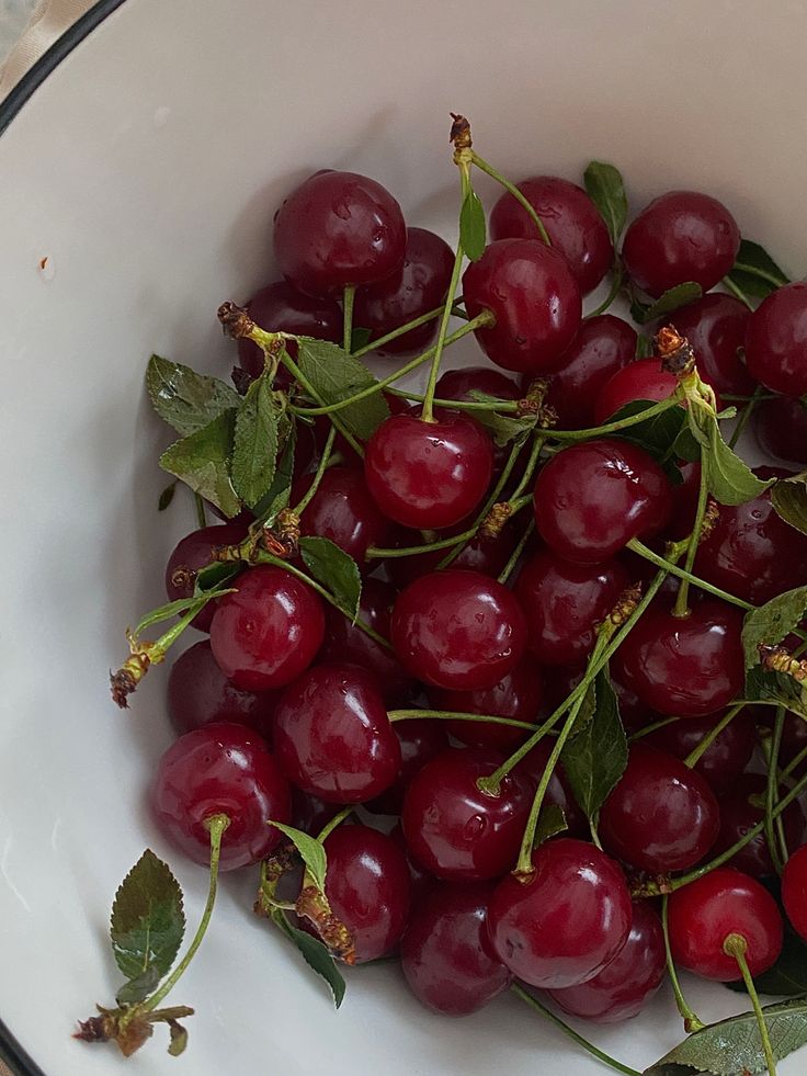 a white bowl filled with cherries on top of a table