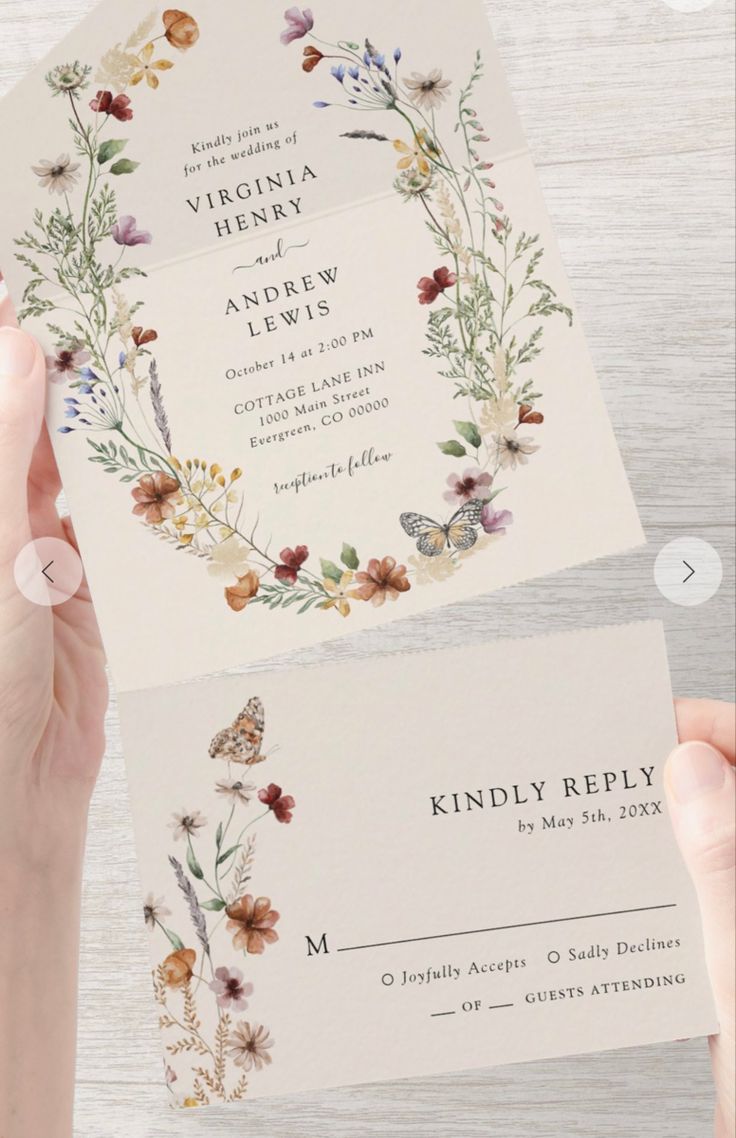 two hands holding wedding cards with flowers and butterflies on them, one has a butterfly in the middle