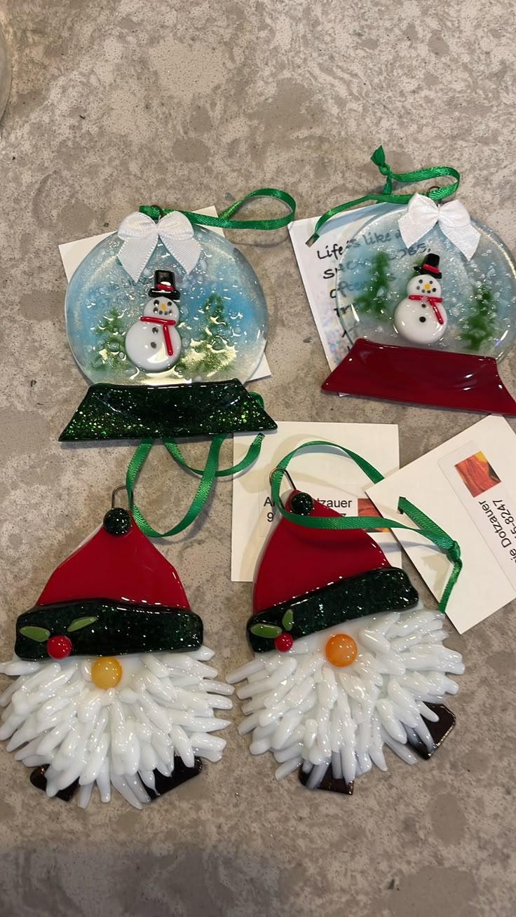 three snowmen with hats and scarfs hanging from christmas decorations on a table top