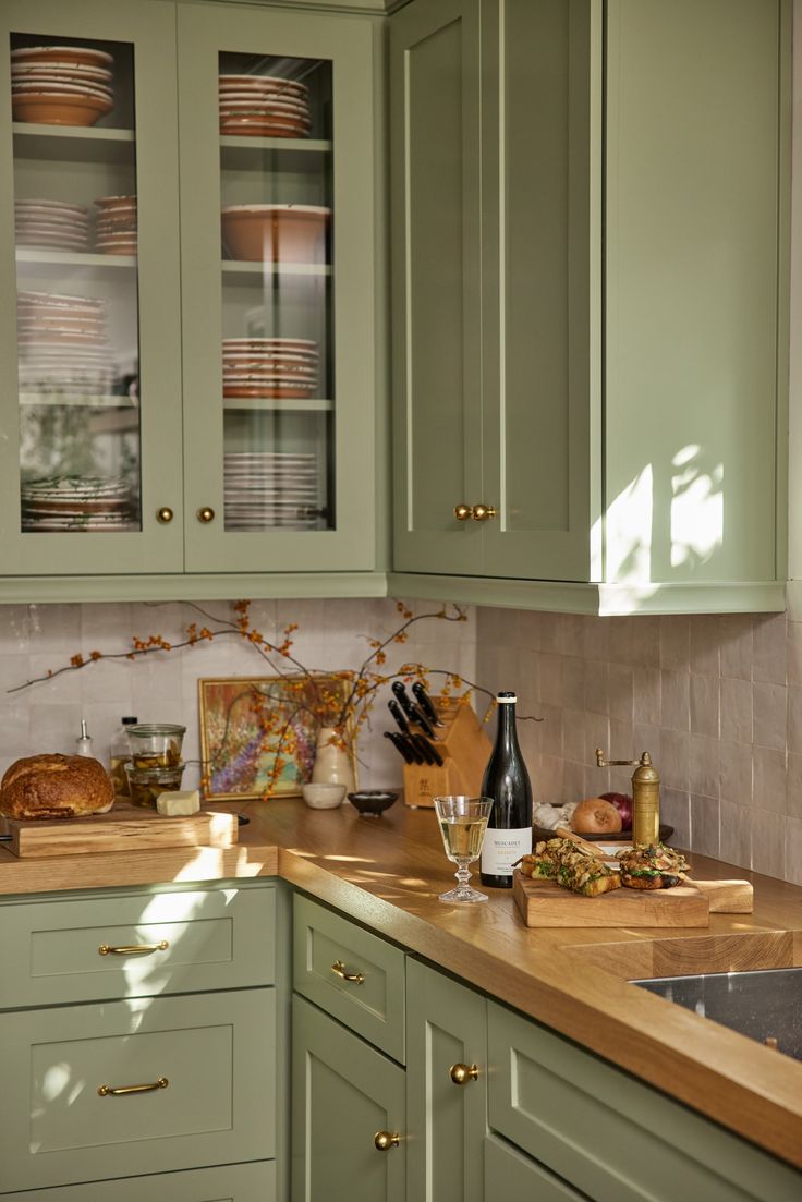 a kitchen with green cabinets and wooden counter tops