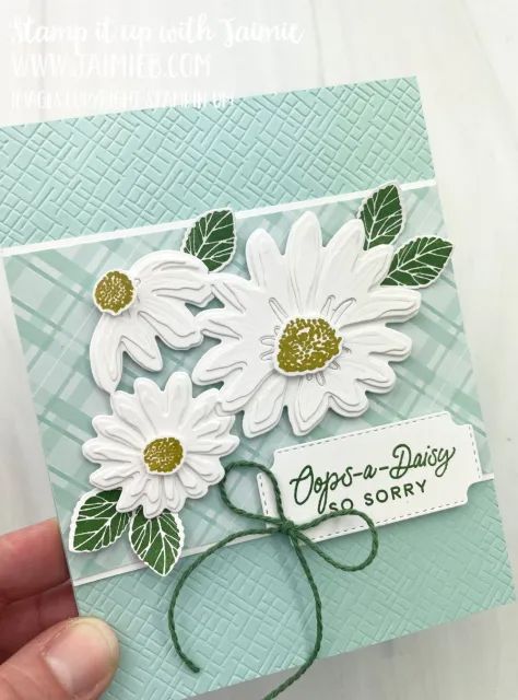 someone is holding up a card with daisies on it and the words pop - n - daisy are written in green