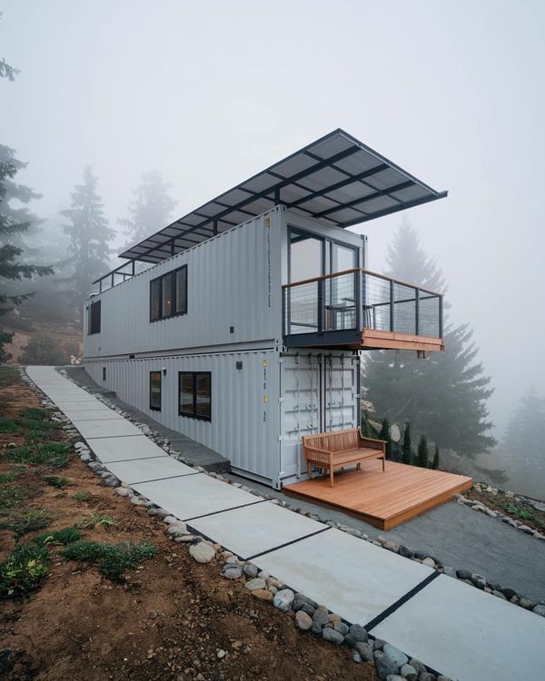 a house made out of shipping containers sitting on top of a hill