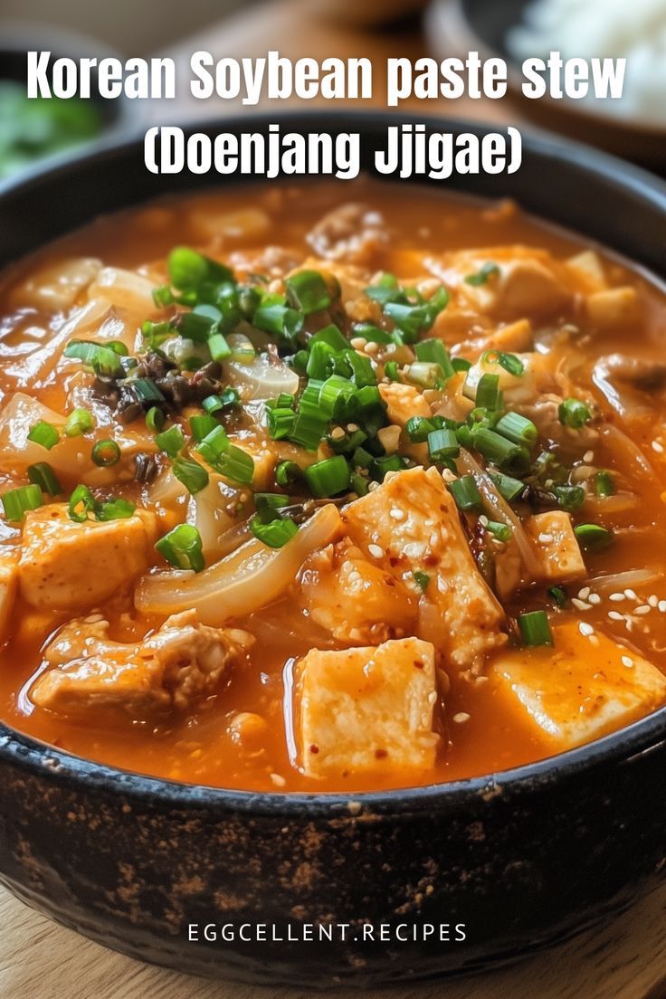 korean soybean paste stew with tofu and green onions in a black bowl