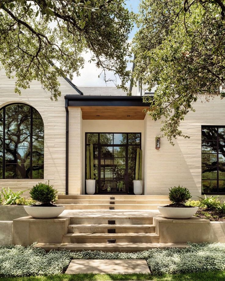 a white house with two large planters on the front porch and steps leading up to it