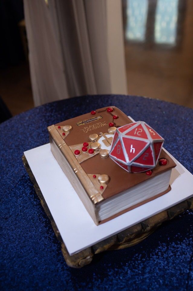 a red and white cake sitting on top of a table next to an open book