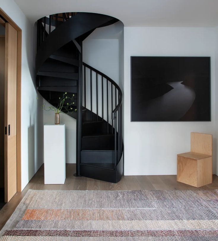 there is a spiral staircase in the living room with pictures on the wall behind it