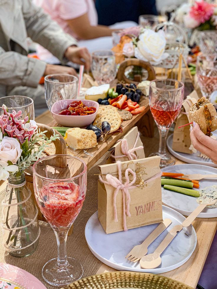 people sitting at a table with food and wine glasses on top of it, all holding utensils