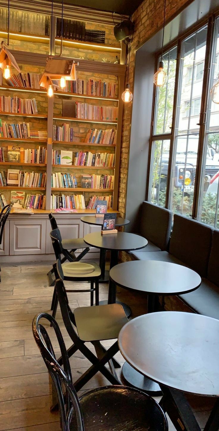 tables and chairs are lined up in front of a bookshelf full of books