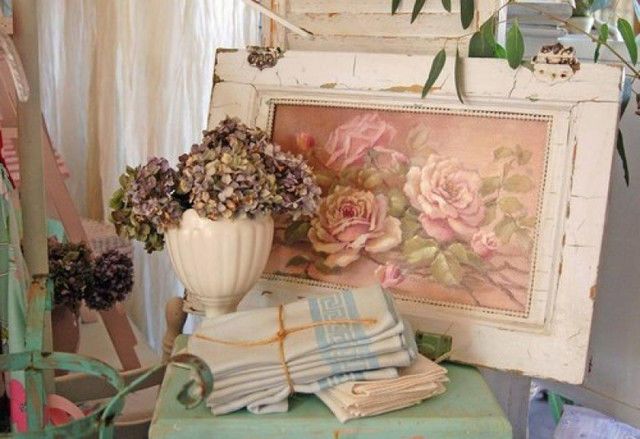 a vase filled with flowers sitting on top of a green stool next to a painting