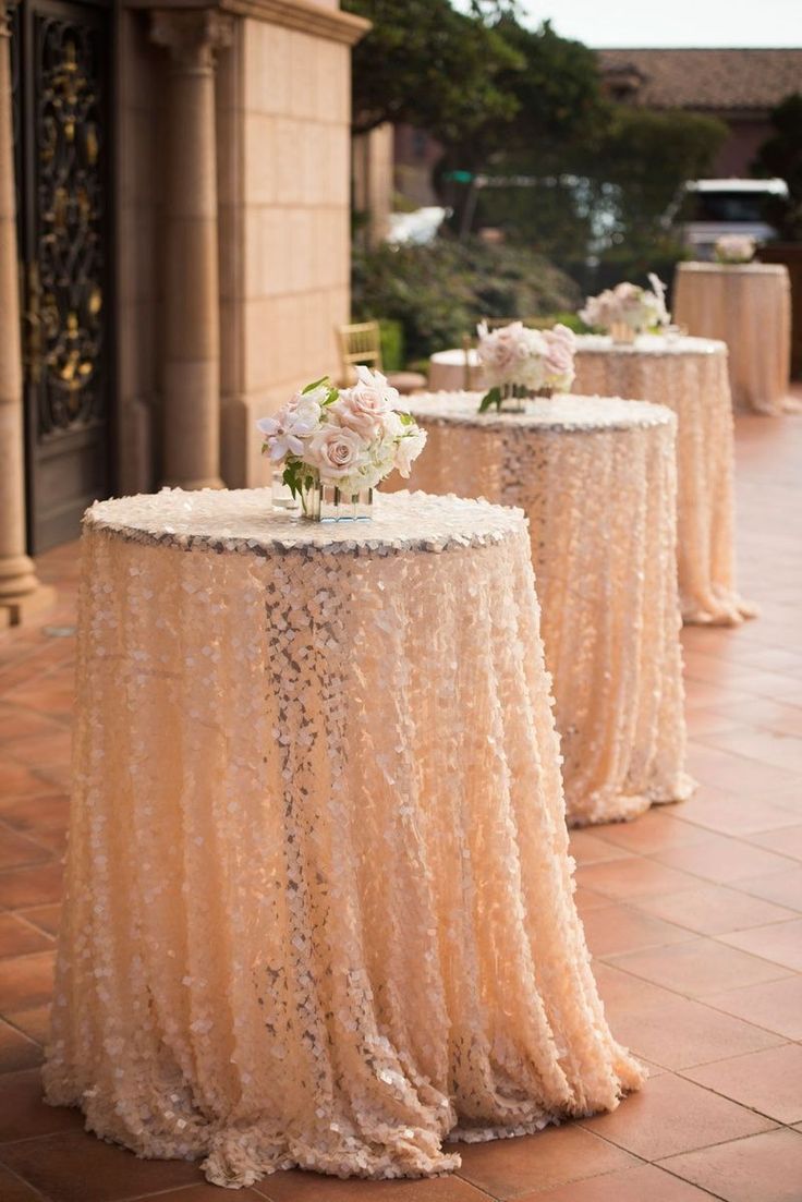 two tables covered in sequins and vases with flowers on them are sitting side by side