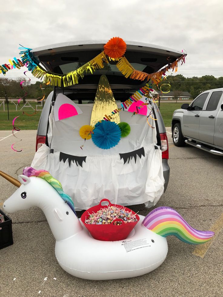 an inflatable unicorn is parked next to a car with decorations on the back