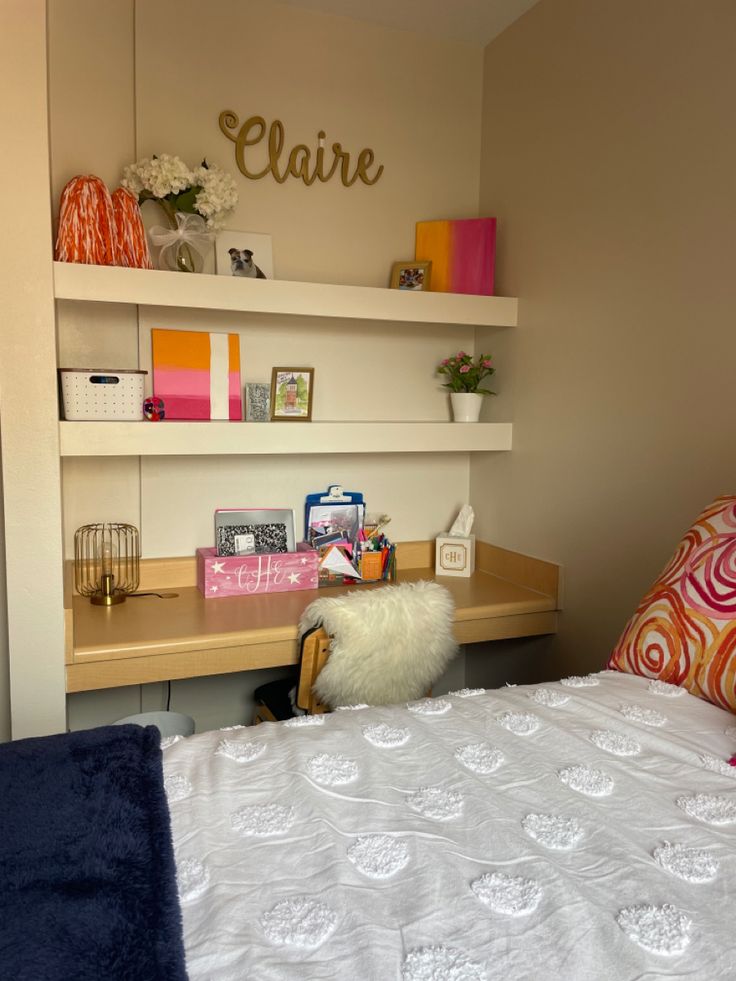 a bedroom with a bed, desk and shelves on the wall above it's headboard