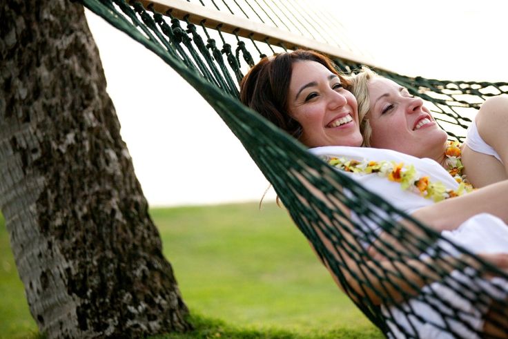 two women are laying in a hammock together