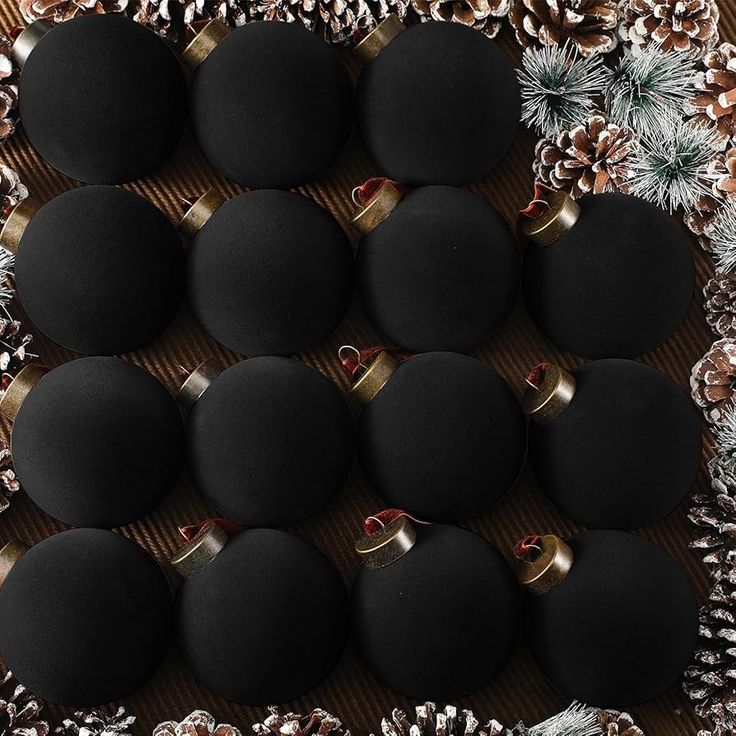 twelve black balls with gold rings and pine cones