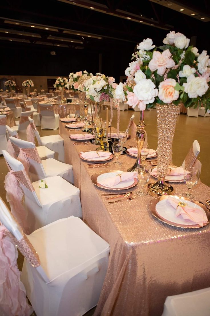 a table set up for a formal function with pink and white flowers in vases