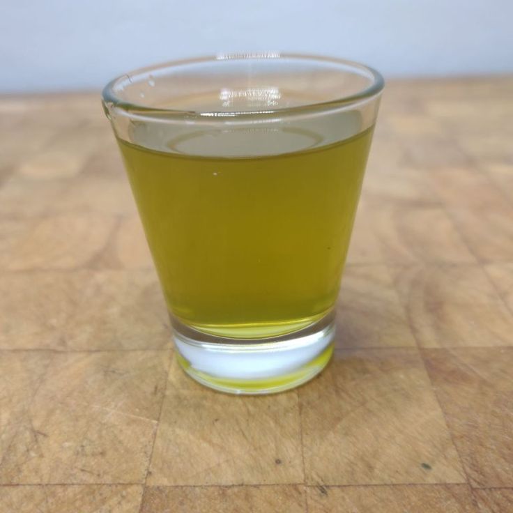 a glass filled with liquid sitting on top of a wooden table