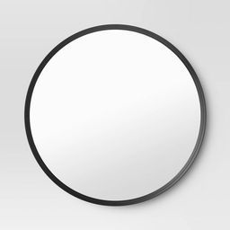 a round mirror on the wall with black trim around it's edges and bottom edge