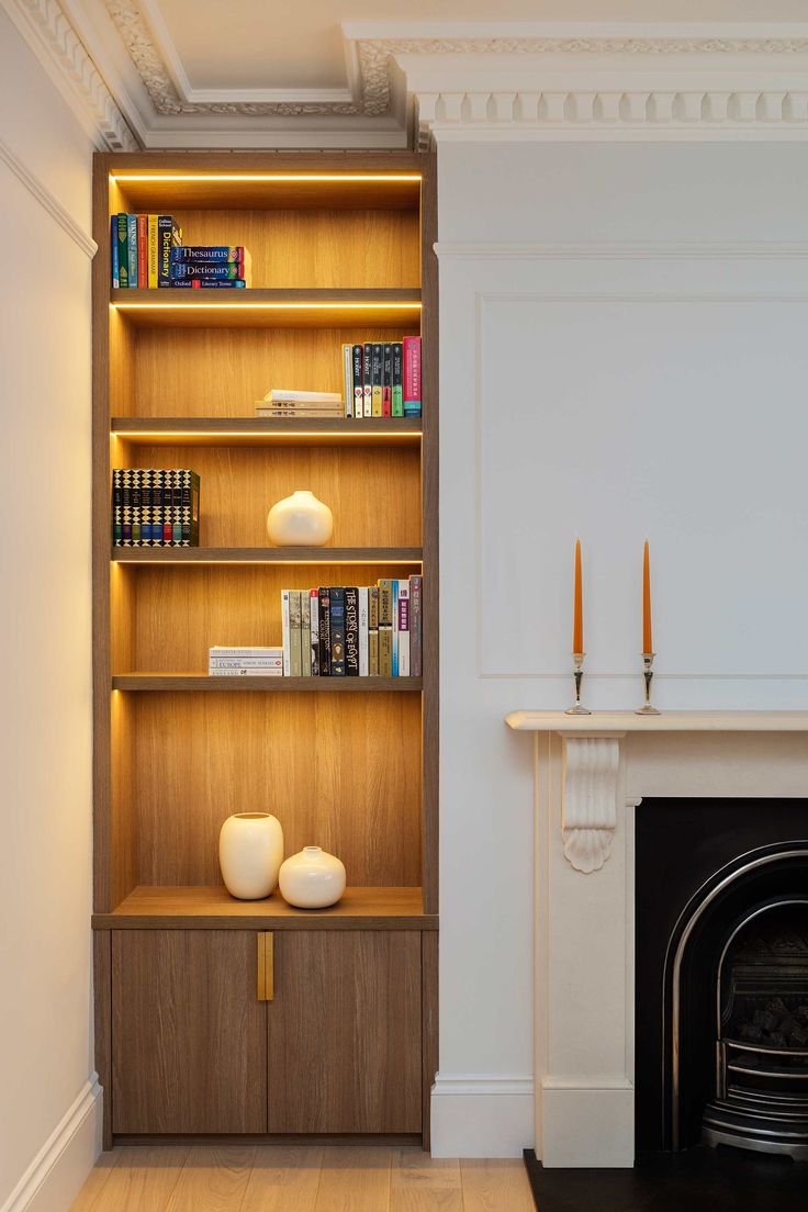 a room with a fireplace, bookshelf and two candles on the mantles