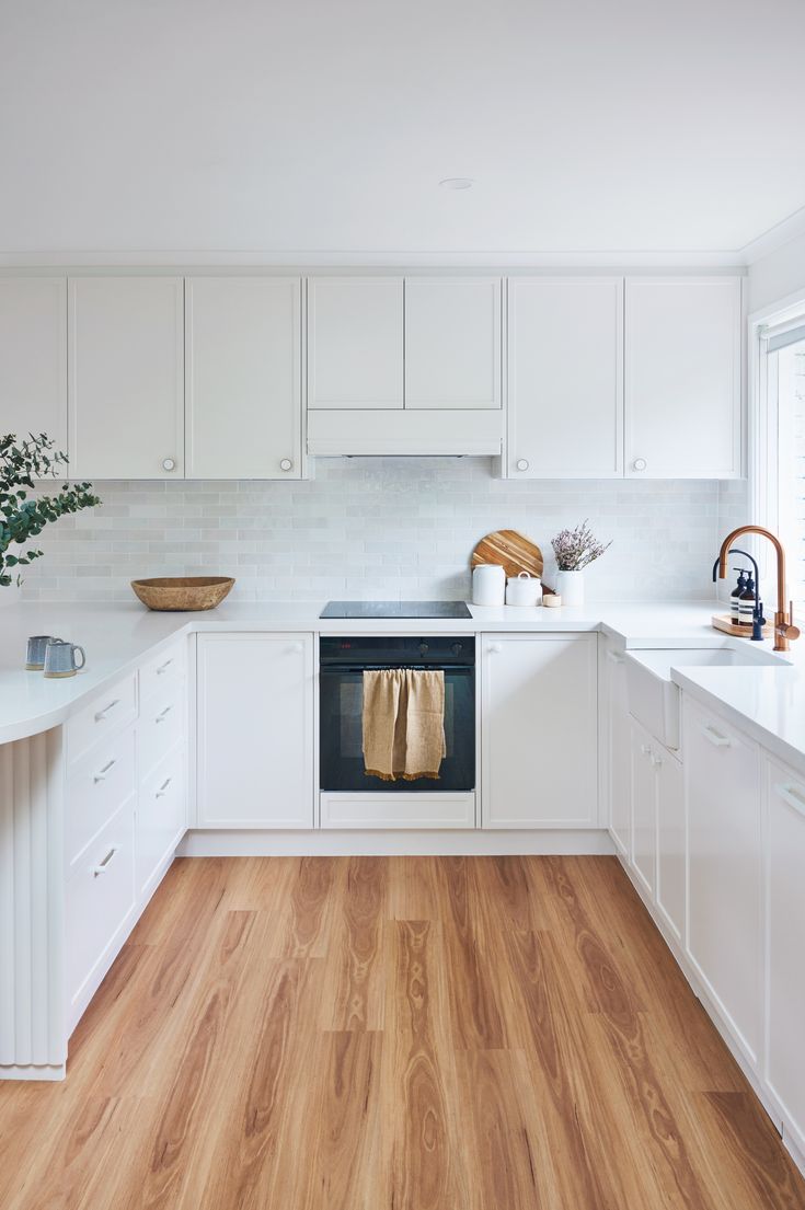 a kitchen with white cabinets and wood floors