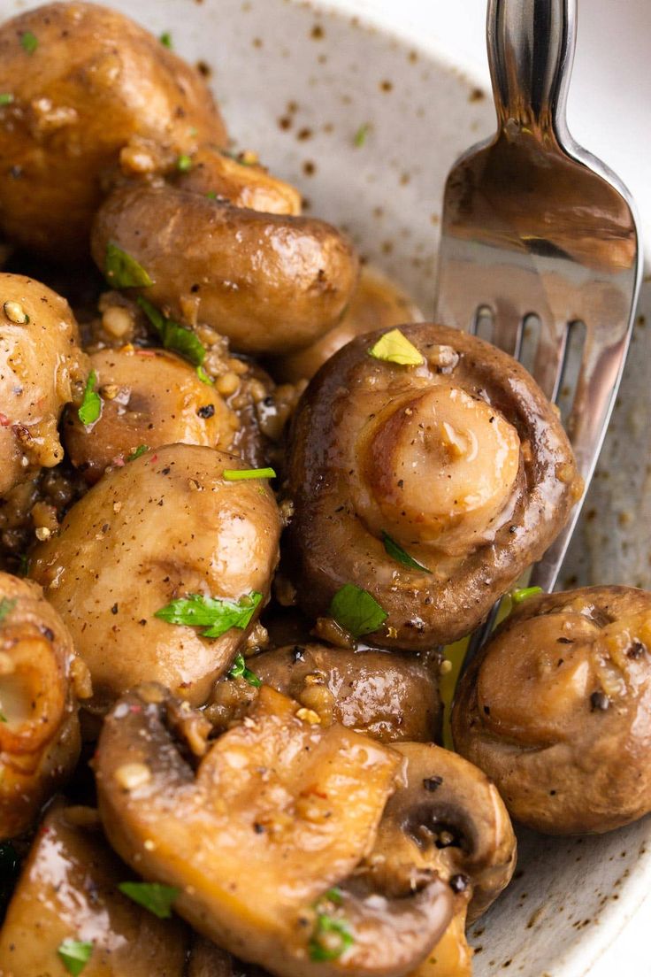 a white bowl filled with mushrooms and a fork