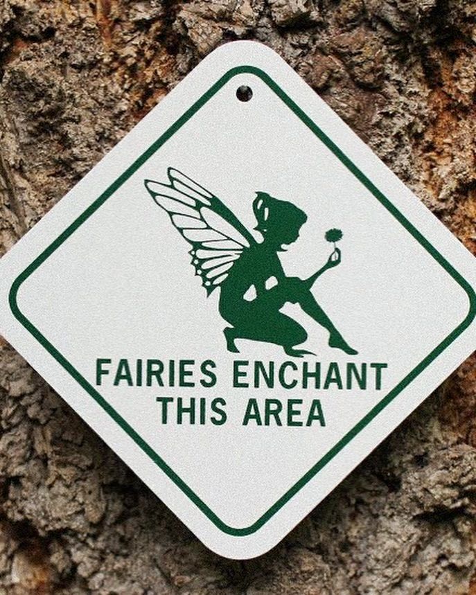 a sign that says fairies enchant this area on a tree