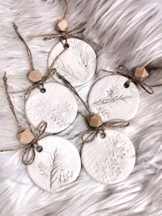 four silver christmas ornaments tied with twine on white furnishing, top view