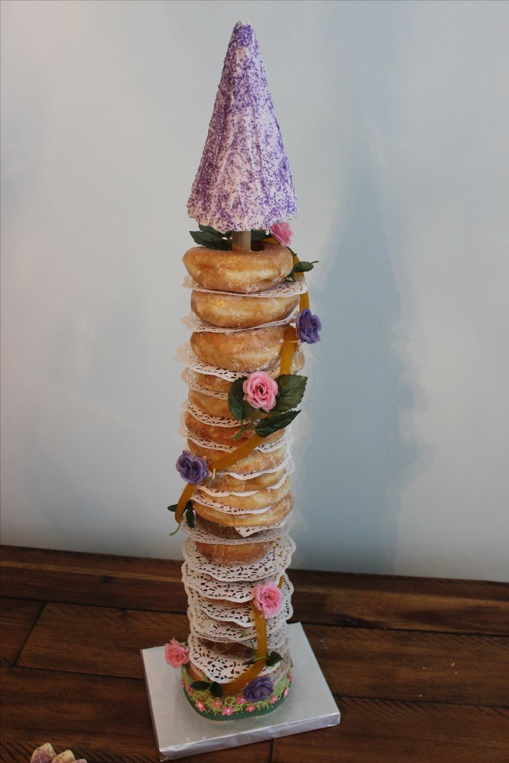 a tall stack of doughnuts sitting on top of a table next to flowers