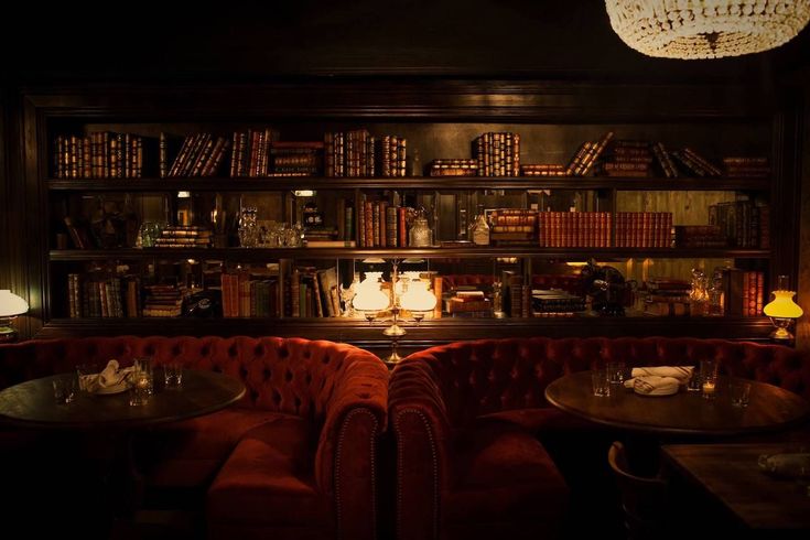 two red booths with tables and chairs in front of bookshelves filled with books