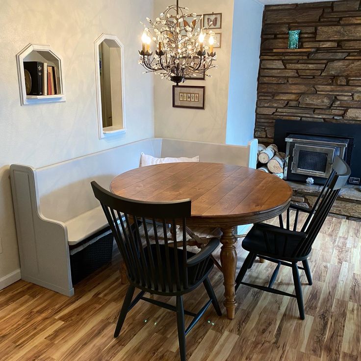 a dining room table with four chairs and a bench in front of the fire place