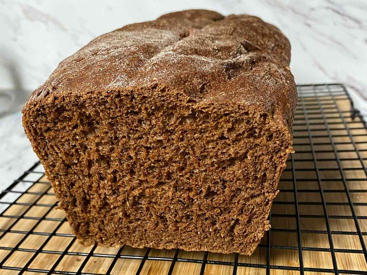 a loaf of brown bread sitting on top of a cooling rack