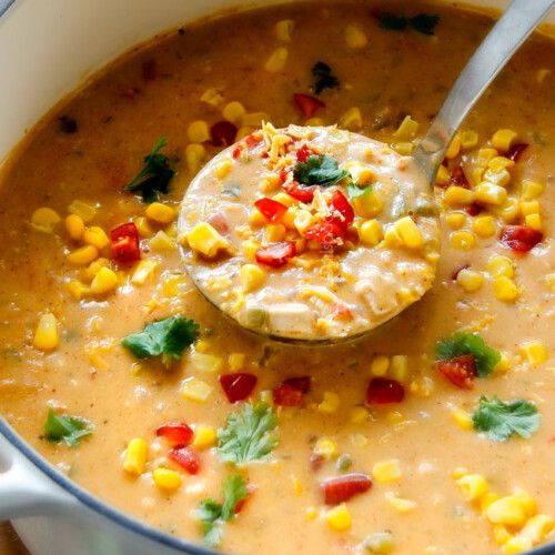 a ladle full of soup with corn and cilantro on the side, ready to be eaten