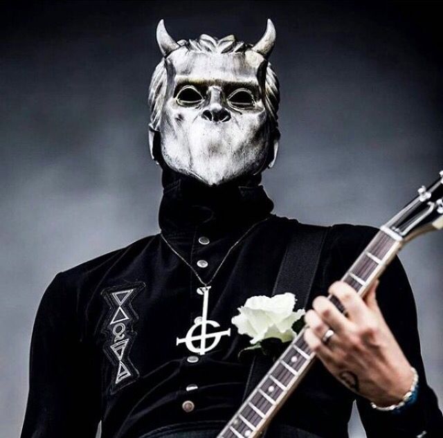 a man wearing a horned mask and holding a guitar in front of him with his face painted white