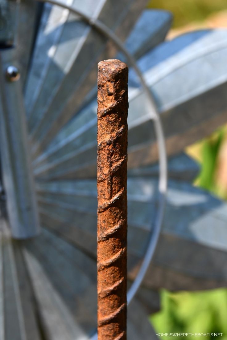 an old rusted metal pole in front of a spinning wheel