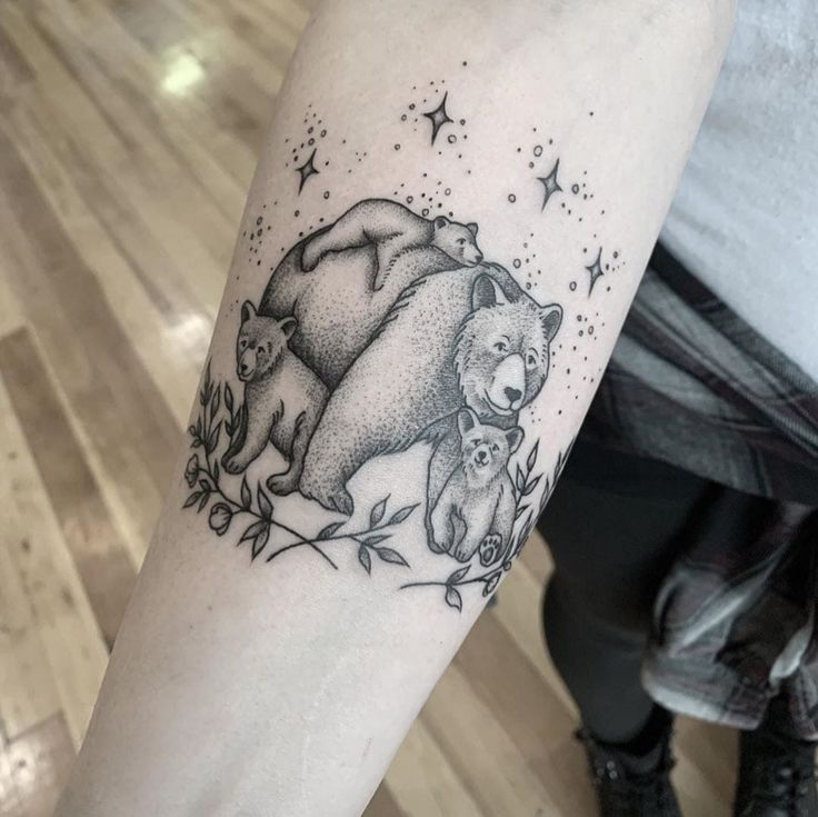 a bear and cub tattoo on the left arm, with stars above it in the background