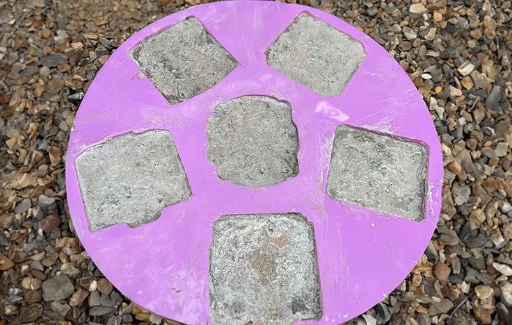 a purple frisbee sitting on top of a pile of rocks next to gravel