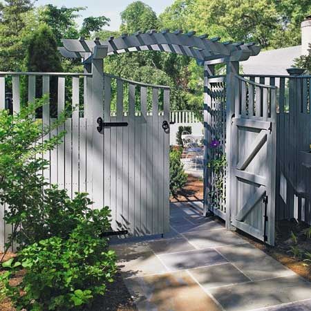 an open gate leading into a garden with potted plants