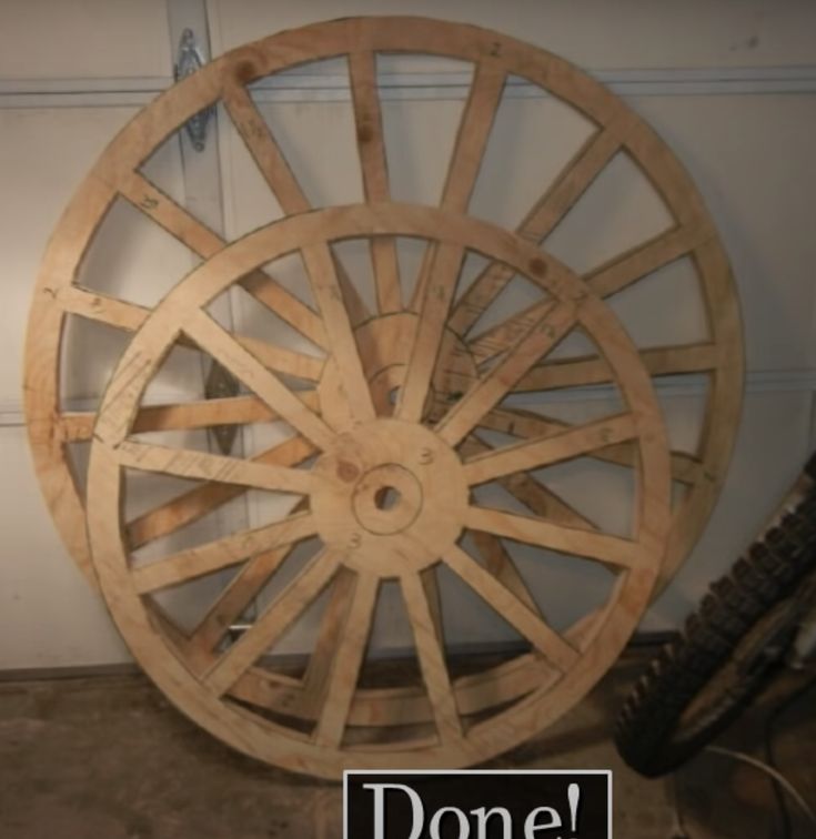 a wooden wagon wheel sitting on top of a garage floor next to a sign that says done