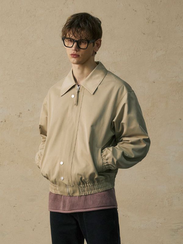 This is a comfortable and casual blouson jacket that is made out of sturdy satin cotton fabric with subtle glow. With a minimal yet unique design with a placket on the front and 3 dimensional sleeve pattern, it gives a casual and refined look. - Oversized silhouette- Dropped shoulder line- Front placket and 4 piece snap buttons- Dart detail on the sleeve - YKK zipper closure Cream Cotton Outerwear With Button Cuffs, Modern Beige Collared Outerwear, Modern Cotton Outerwear With Lapel Collar, Modern Cotton Outerwear With Button Cuffs, Modern Cotton Outerwear With Ribbed Cuffs, Modern Beige Outerwear With Button Closure, Spring Beige Outerwear With Concealed Placket, Modern Beige Outerwear With Hidden Button Closure, Modern Outerwear With Button Cuffs For Spring