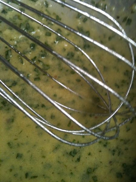 a metal whisk in a bowl filled with broccoli and cheese sauce