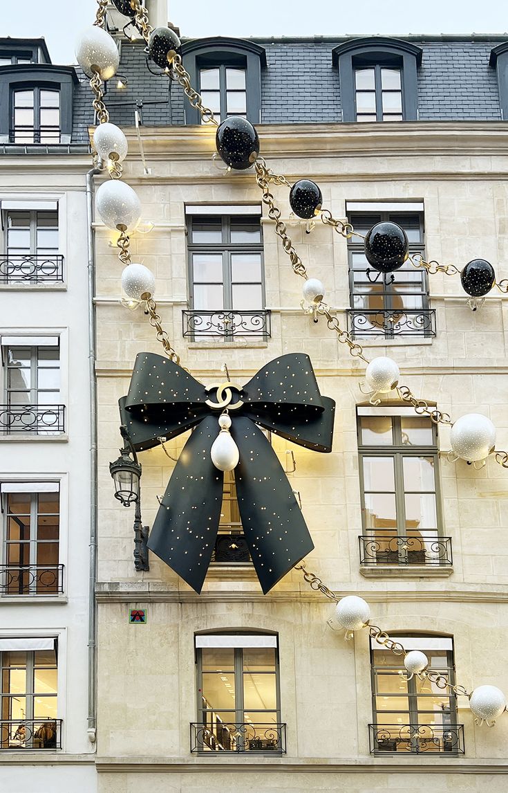 a large black and white bow on the side of a building with christmas decorations hanging from it's sides