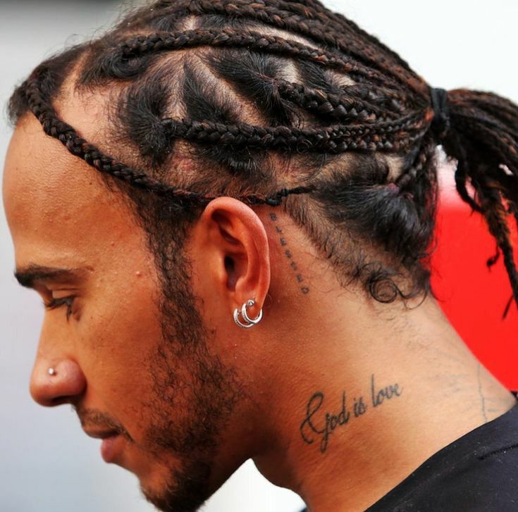 a close up of a person with dreadlocks and tattoos on his head looking to the side