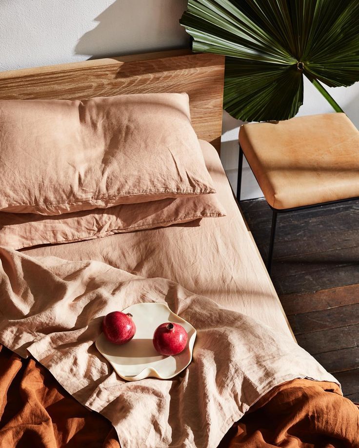 two apples are on a plate in the middle of an unmade bed with brown sheets