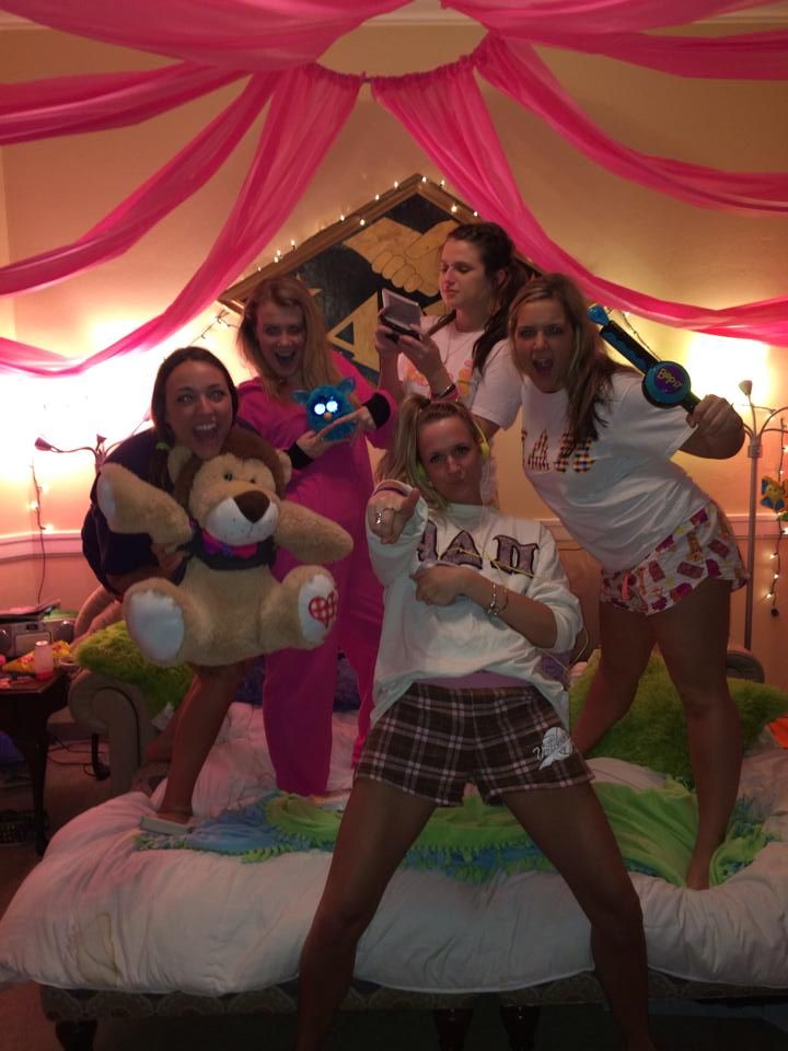 four girls are posing on a bed with stuffed animals and teddy bears in the background