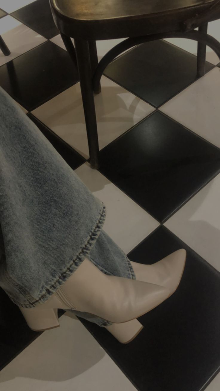 a pair of white high heeled shoes sitting on top of a black and white checkered floor