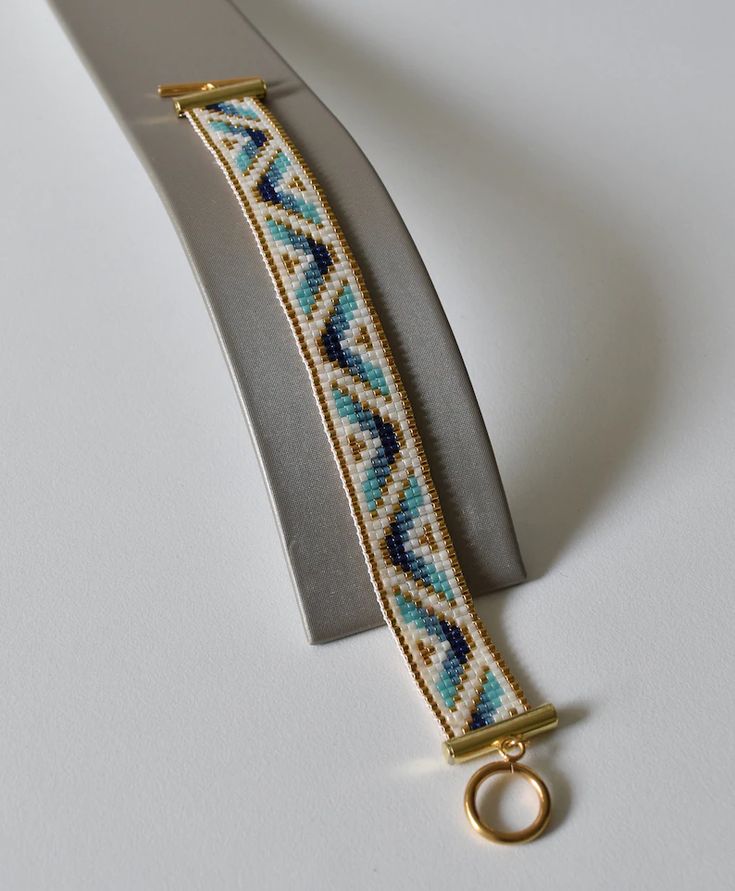 a pair of scissors sitting next to a beaded bracelet on top of a white surface