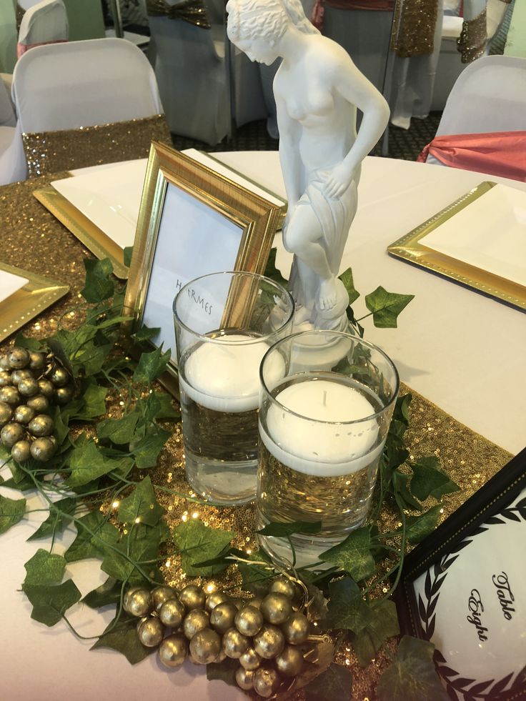 a table topped with two glasses filled with water and candles next to a framed photo